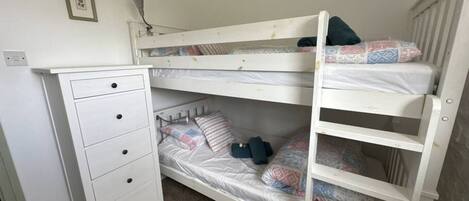 Un letto a castello con una cassettiera e una lampada.