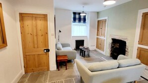 A living room with a sofa, a small table, a lamp, and a fireplace. - 8 Duke Street in Cornwall (Launceston)