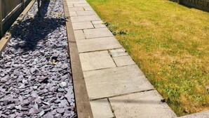 A stone house with a fenced backyard, a paved pathway, and a small tree. - 8 Duke Street in Cornwall (Launceston)