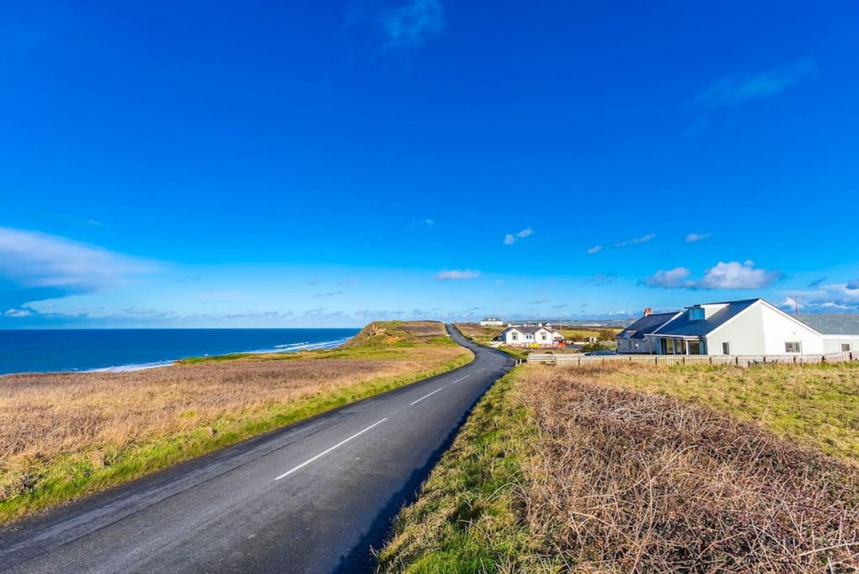 A coastal road with houses on the right.