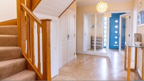 A staircase leading to a hallway with a chandelier, a blue door, and a glass table.