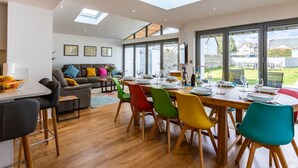 A modern dining area with a high ceiling, skylights, and large windows offering a view of the outdoors. - Number 15 in Cornwall (Bude)