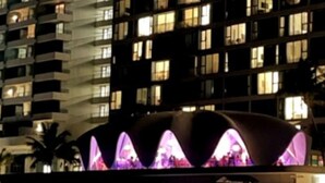A multi-story hotel with balconies and a distinctive, illuminated structure in the foreground. - Casa del Sol-unit A Island Escape 3BR Near Hospital Malls (Bayamon)