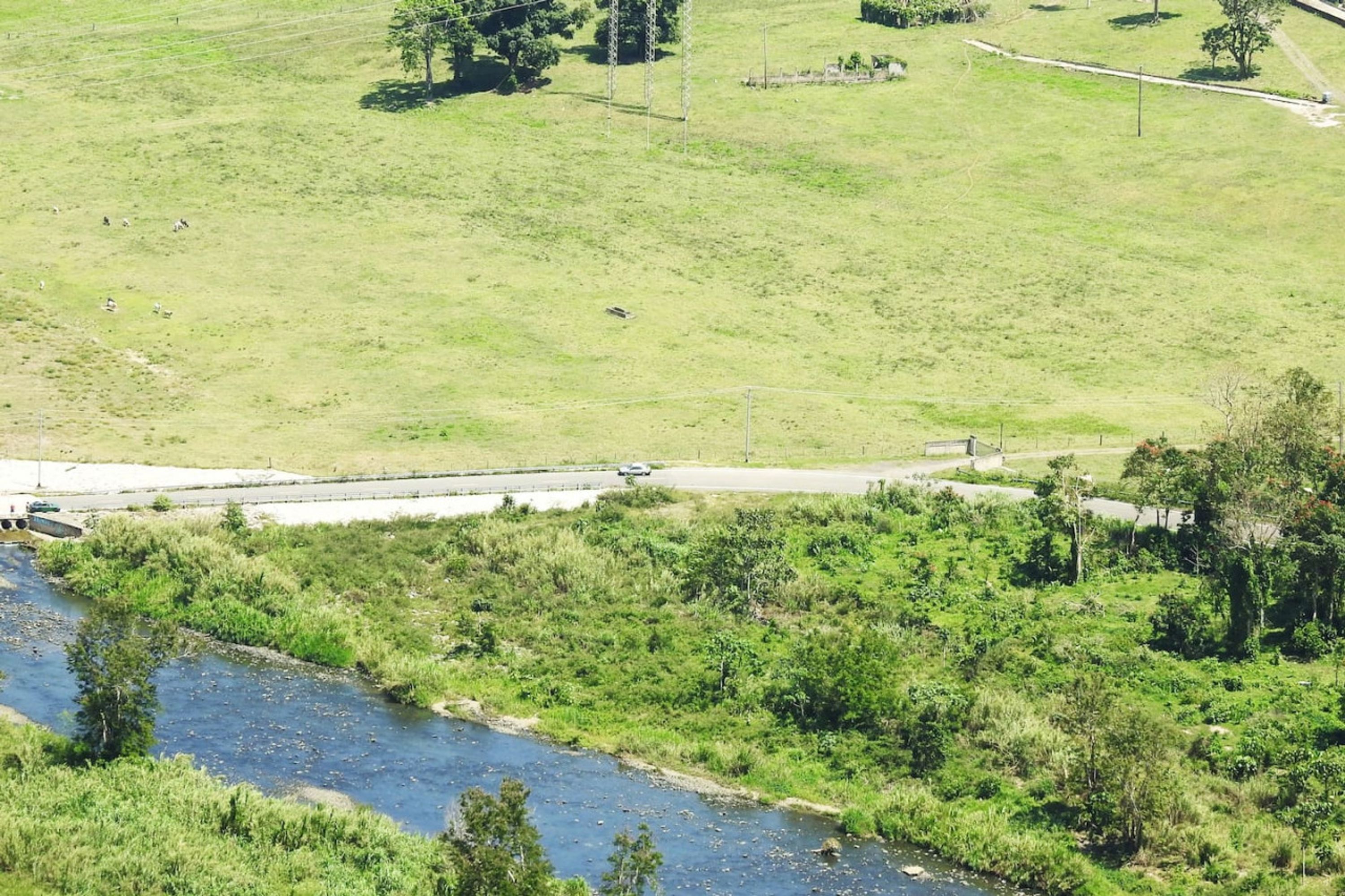 Un paisaje rural con un río, campos de hierba y un puente.