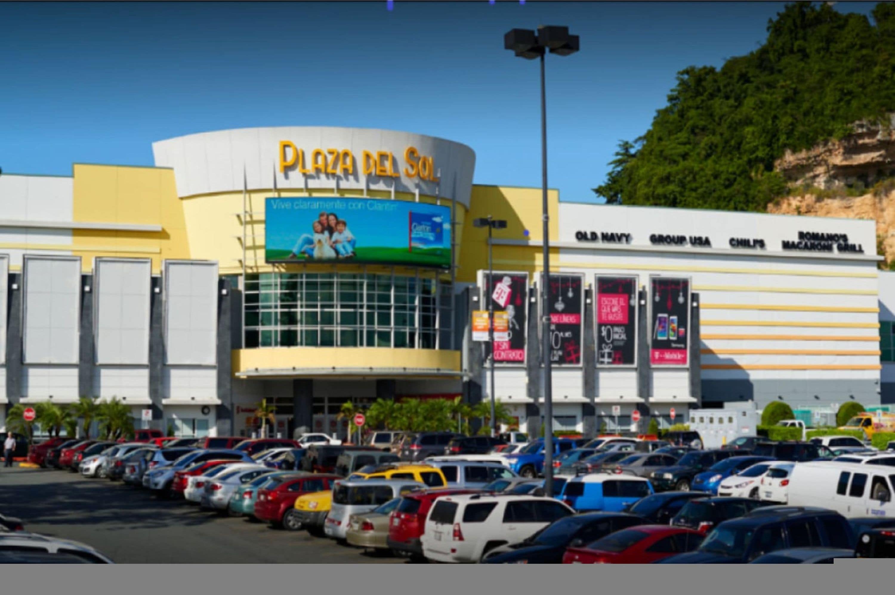 A shopping mall with a large sign reading "Plaza del Sol" and various shops including "Old Navy" and "Group USA".