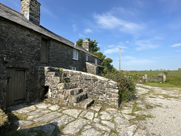 A stone building with a wooden door and a stone staircase leading to a second level. - South Priddacombe in Bolventor (Magherafelt)