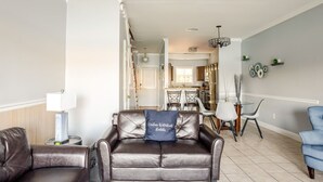 Un salon moderne avec un canapé en cuir, un coin repas comprenant une table et des chaises, et une cuisine en arrière-plan.