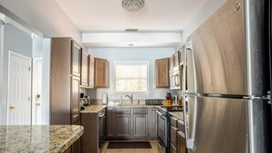 Une cuisine moderne dotée de plans de travail en granit, d’appareils électroménagers en acier inoxydable et d’armoires en bois.