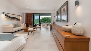 A modern living room with a sofa, coffee table, and chairs, a wooden bench, and a large window with a view of greenery. - Villa Amistad in Punta Mita (Punta de Mita)