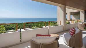 Un balcon avec vue sur la mer, des meubles en osier et une rambarde en bois.