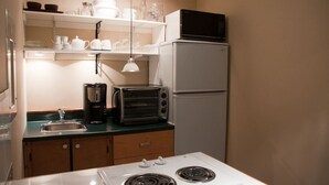 A compact kitchen with a white stove, a toaster, a coffee maker, and a refrigerator. - Bree s by the Sea - Ocean View Large 2 Person Tub (Nanoose Bay)