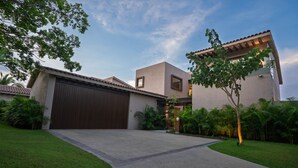 A modern house with a large garage, a well-maintained lawn, and a clear sky. - Villa Amada in Punta Mita (Punta de Mita)