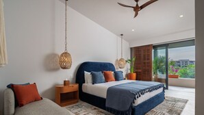 A modern bedroom with a large bed, a sofa, a wooden nightstand, and a ceiling fan. - Villa Amada in Punta Mita (Punta de Mita)