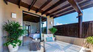 An outdoor seating area with a sofa and two potted plants, a wooden pergola, and a view into a bedroom. - PH Vista Ballena in Punta Mita (Punta de Mita)