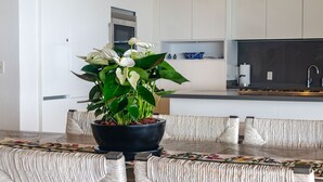 A modern kitchen with white cabinets, a black countertop, and a potted plant on the table. - PH Vista Ballena in Punta Mita (Punta de Mita)