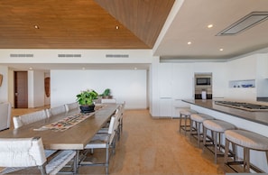 A modern kitchen with white cabinets, a built-in microwave, and a stainless steel range hood. - PH Vista Ballena in Punta Mita (Punta de Mita)