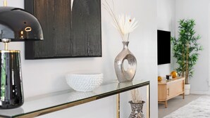 A modern living room with a glass coffee table, a decorative vase, a textured bowl, and a minimalist wall art piece. - Oasis Backyard With Heated Pool Oakland Park (Wilton Manors)