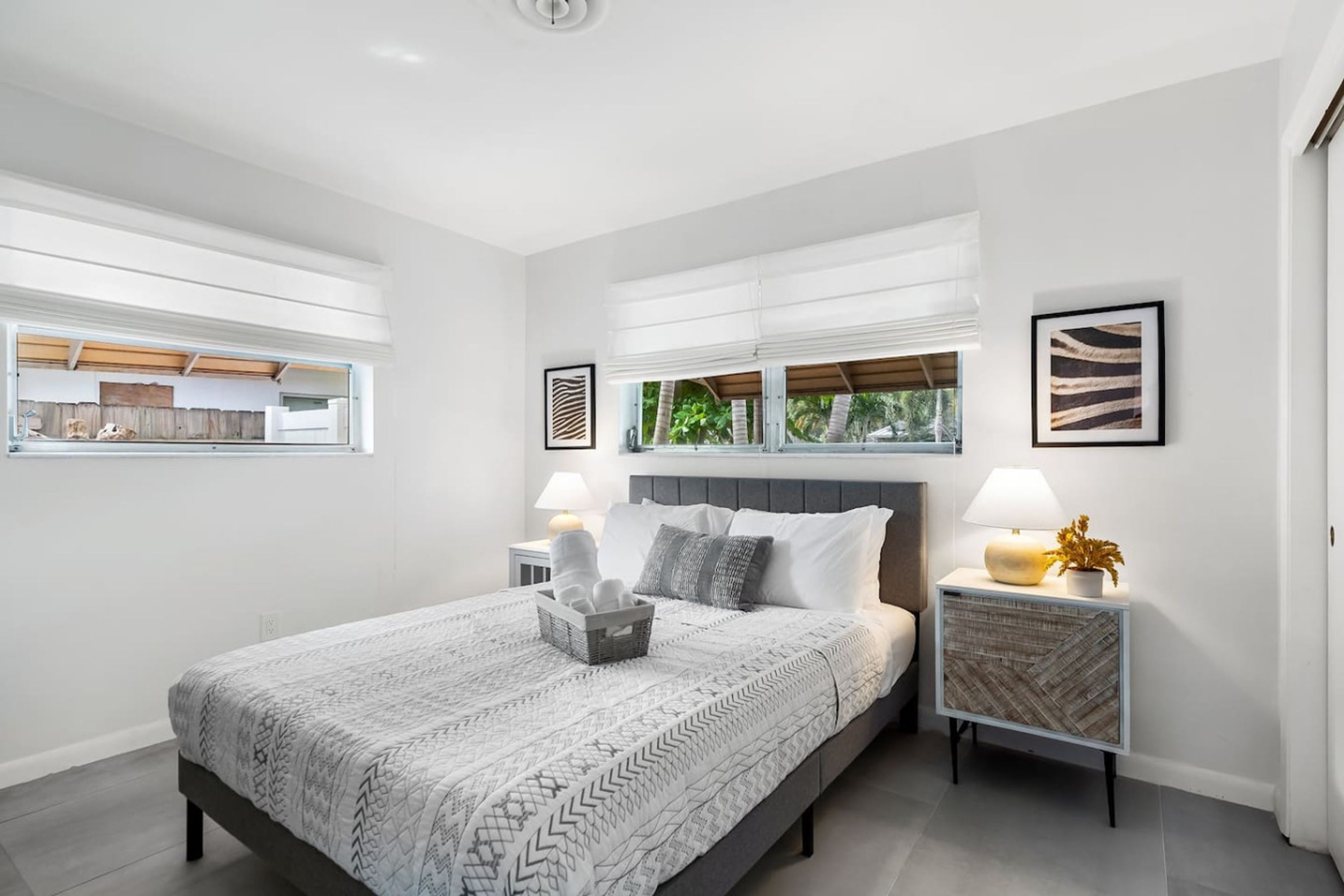 A modern bedroom with a large bed, bedside tables, and artwork on the walls.