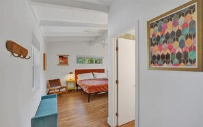Un dormitorio con cama, una banca, una silla, una mesita de noche y una ventana.