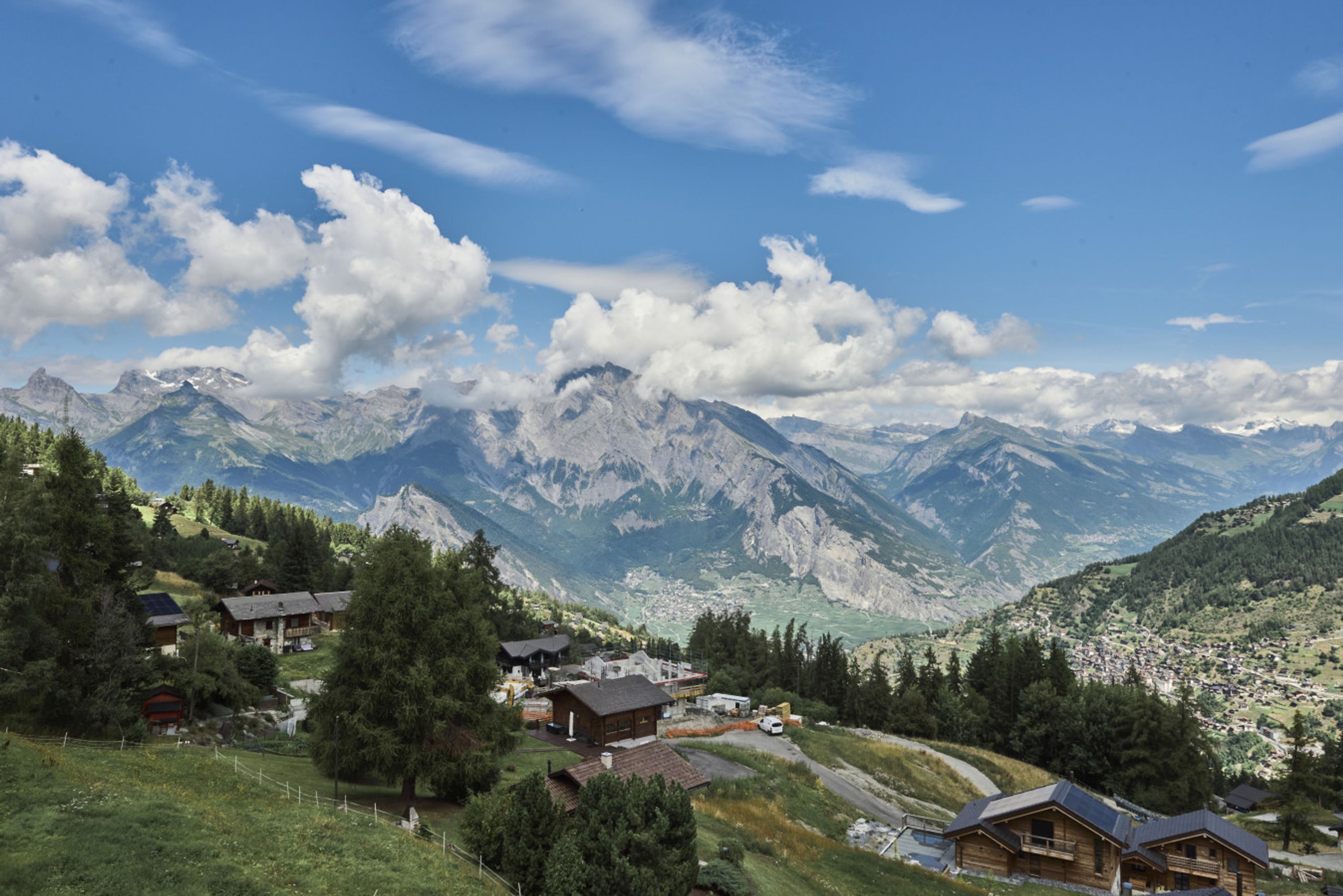 Un village de montagne aux maisons traditionnelles en bois, une route sinueuse et une vallée en contrebas.