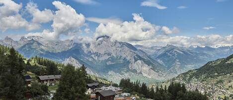 Un village de montagne aux maisons traditionnelles en bois, une route sinueuse et une vallée en contrebas.