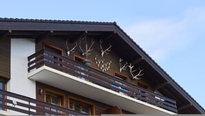 Um edifício com varanda, grades de madeira e chifres de animais fixados.