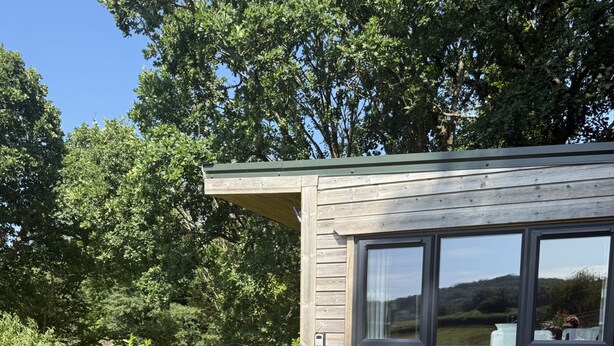 A small wooden cabin with a patio area featuring a round table and two chairs. - The Cabin in Lifton With 1 Bedrooms and 1 Bathrooms (Lifton)