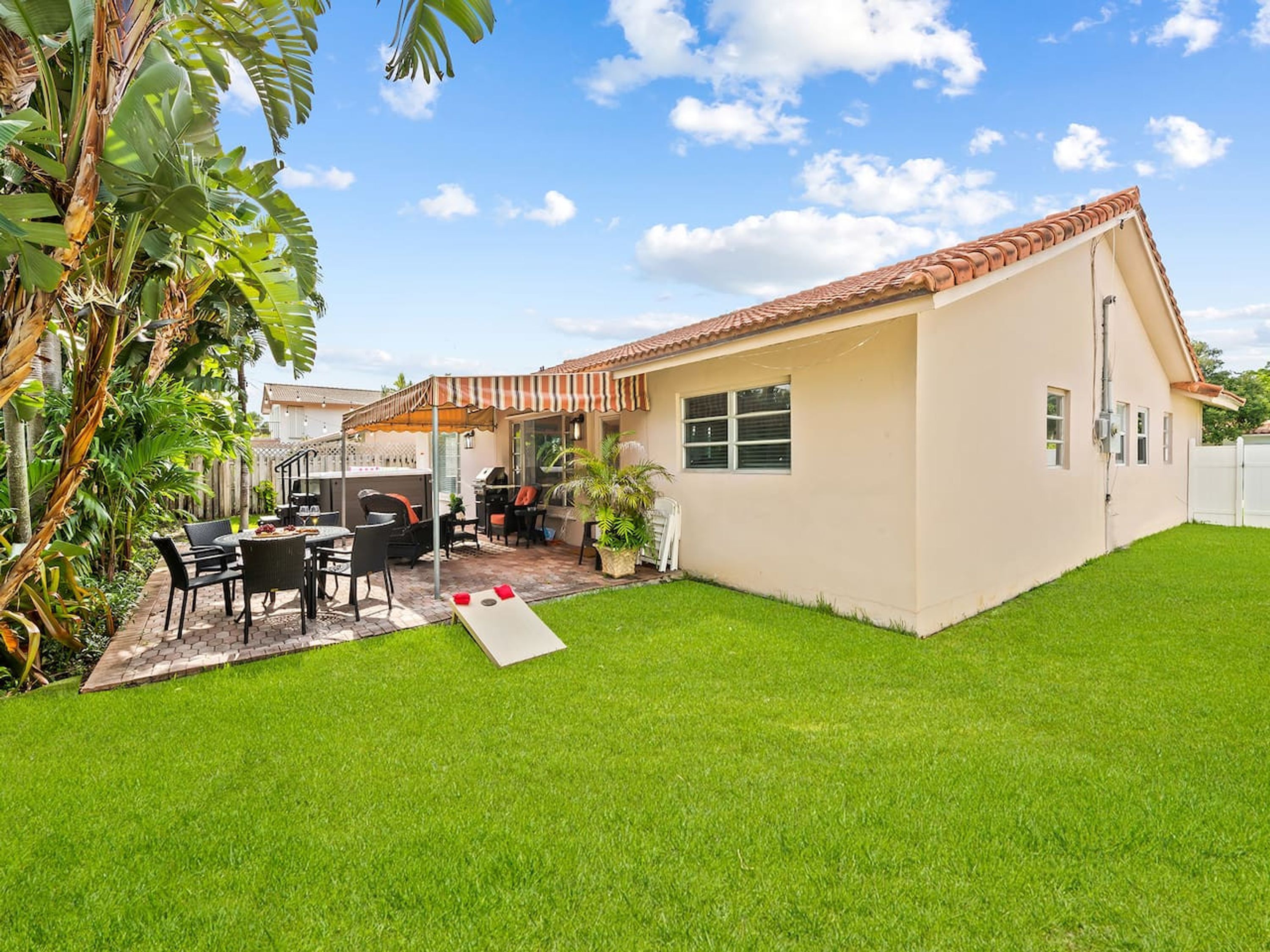 Una casa con patio, mobiliario exterior y un pequeño jardín.