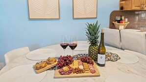 A table set with wine glasses, a bottle of wine, a pineapple, grapes, and various cheeses and meats. - Beach Bungalow Walk to Beach Swimspa Jacuzzi (Lauderdale-by-the-Sea)