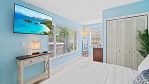 A bedroom with a bed, a desk, a TV, and a closet. - Beach Bungalow Walk to Beach Swimspa Jacuzzi (Lauderdale-by-the-Sea)