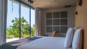 A large bed with white linens, a view of the ocean, and a window with curtains. - Valhalla Luxury Villa (Punta de Mita)