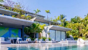 A modern poolside area with lounge chairs and a clear blue pool, surrounded by lush greenery and palm trees. - Valhalla Luxury Villa (Punta de Mita)