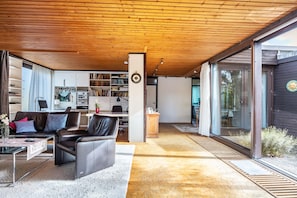 A modern living room with a wooden ceiling, leather sofa, and a bookshelf. - 128 sqm/4 rooms: sunny feel-good bungalow with garden (Braunschweig)