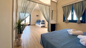 A bedroom with a bed, a nightstand, a mirror, and a potted plant. - Michail Suites Afiartis Diakoftis (Karpathos)