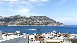 A coastal town with buildings in the foreground and a mountain in the background. - Aerase Apartment in Karpathos (Karpathos)