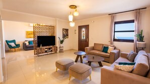 A modern living room with a flat-screen TV, two sofas, a coffee table, and a decorative partition. - Villa Danai in Volada (Karpathos)