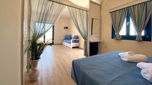 A bedroom with a bed, a bedside table, a mirror, a potted plant, and a view of a balcony.