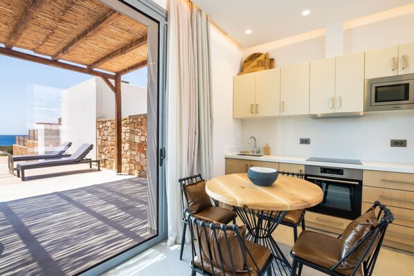 A modern kitchen with a round table, chairs, and a built-in oven.