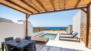 Un espace extérieur abrité comprenant une piscine, des chaises longues et une table avec des chaises.
