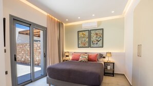 Une chambre dotée d’un grand lit, d’une porte-fenêtre coulissante donnant sur un balcon et de deux œuvres d’art encadrées accrochées au mur.