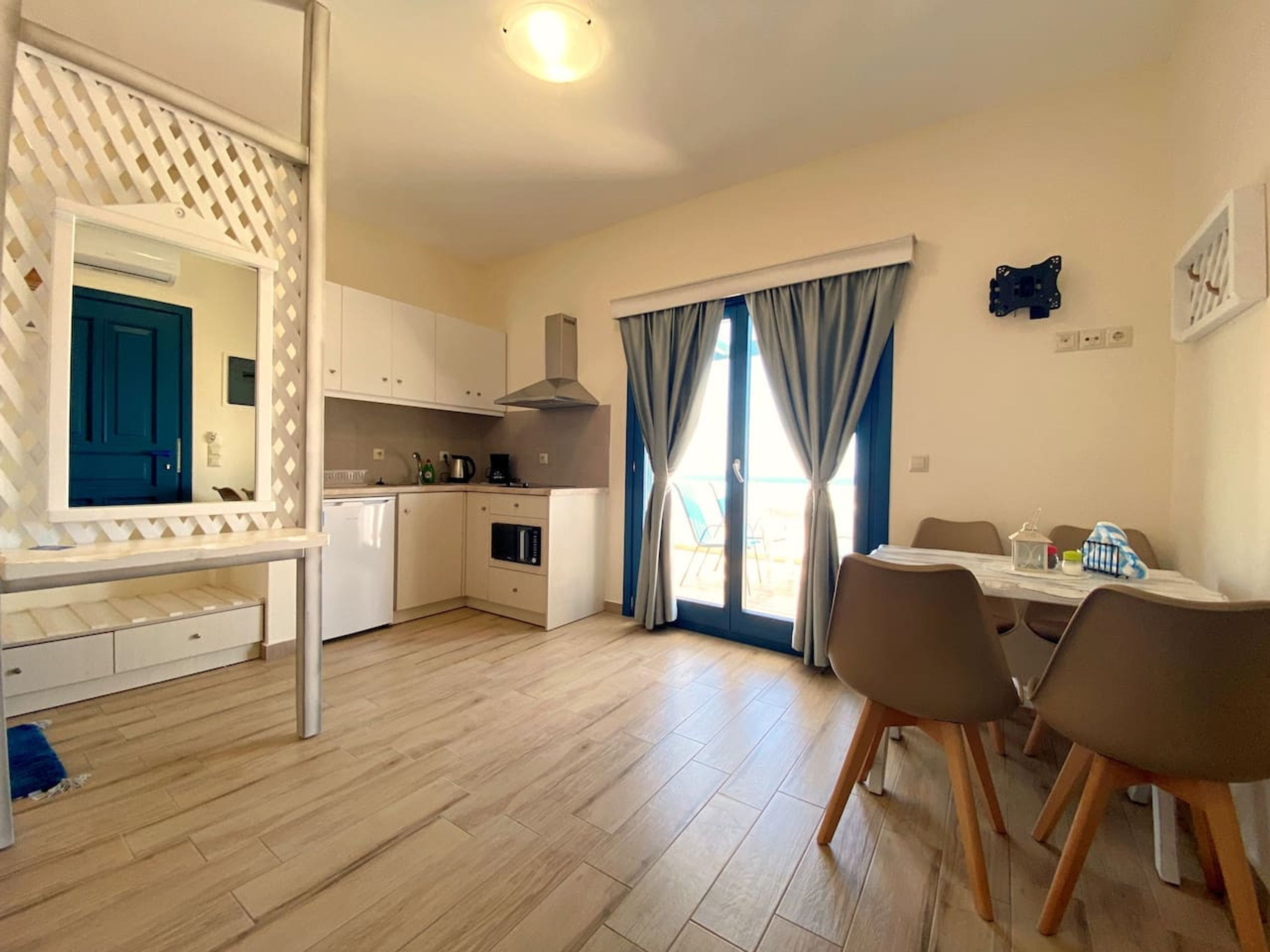 A compact kitchen with a dining area, a blue door, and a view through the window.