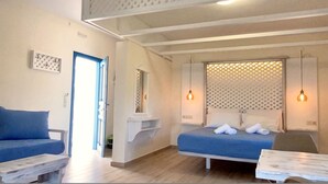 Une chambre à coucher avec un lit, un canapé bleu, une petite table et un luminaire suspendu.