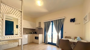 Een moderne keuken met witte kasten, een ingebouwde oven en een eethoek met een tafel en stoelen.