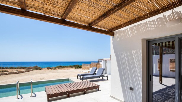 A pool area with lounge chairs and a wooden deck overlooking a beach.