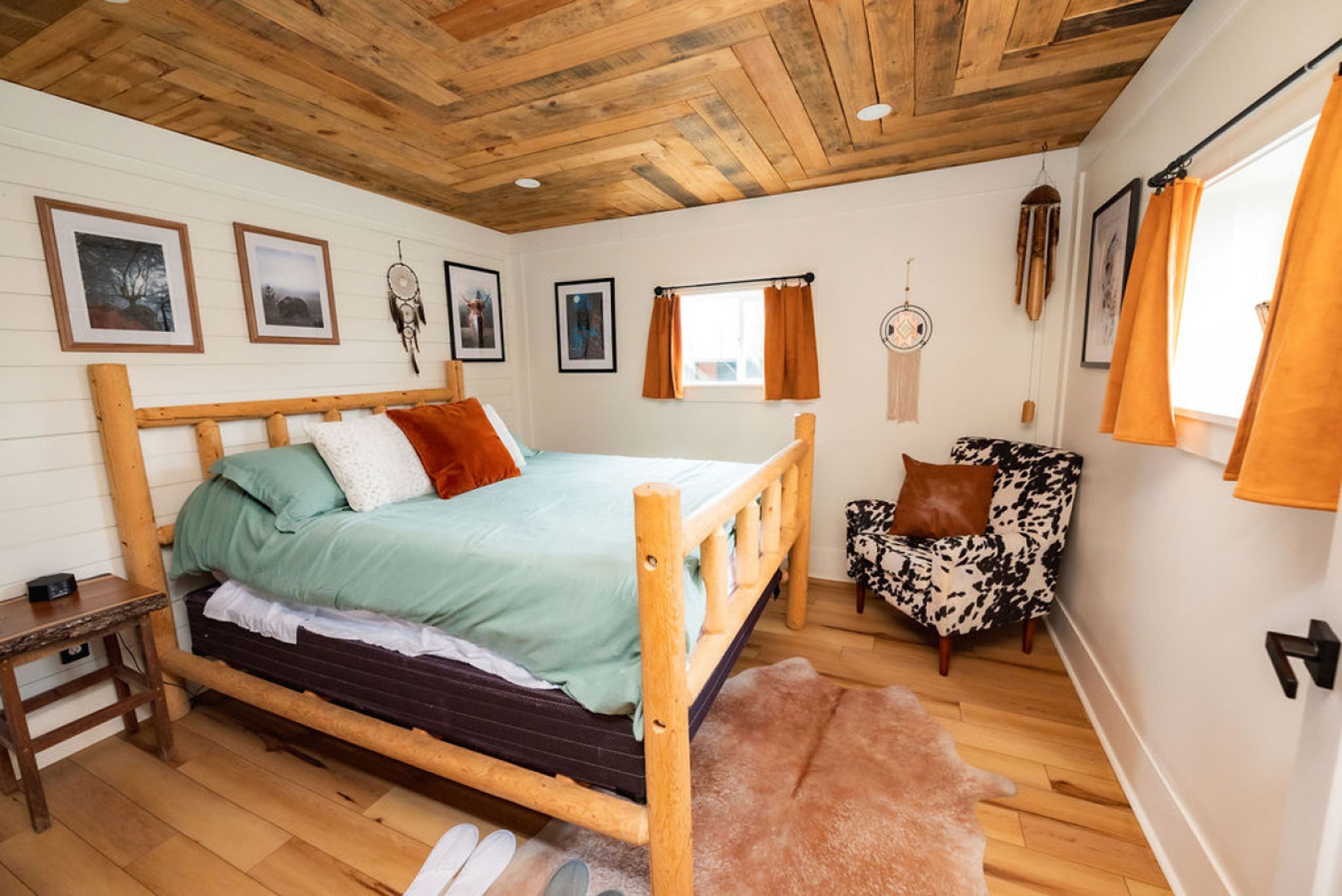 A cozy bedroom with a wooden bed, a small side table, a chair, and a fluffy rug.