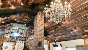 A rustic interior with exposed wooden beams, a brick column, and a chandelier.