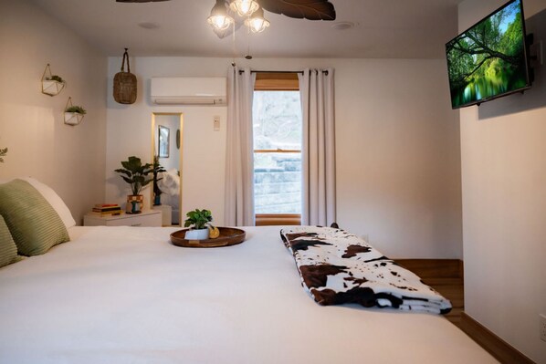 Un dormitorio con cama, televisión y ventana con cortinas.