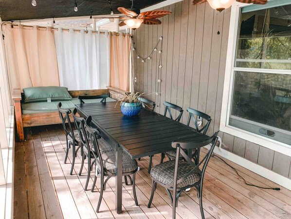 A dining area with a wooden table, black chairs, a blue vase, and a ceiling fan.