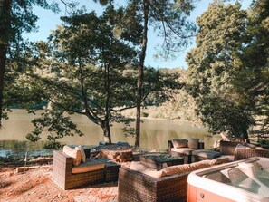 Un área de estar al aire libre junto al lago, con mobiliario de mimbre y un jacuzzi.