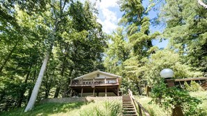 Un escalier en bois mène à une maison entourée d’arbres.